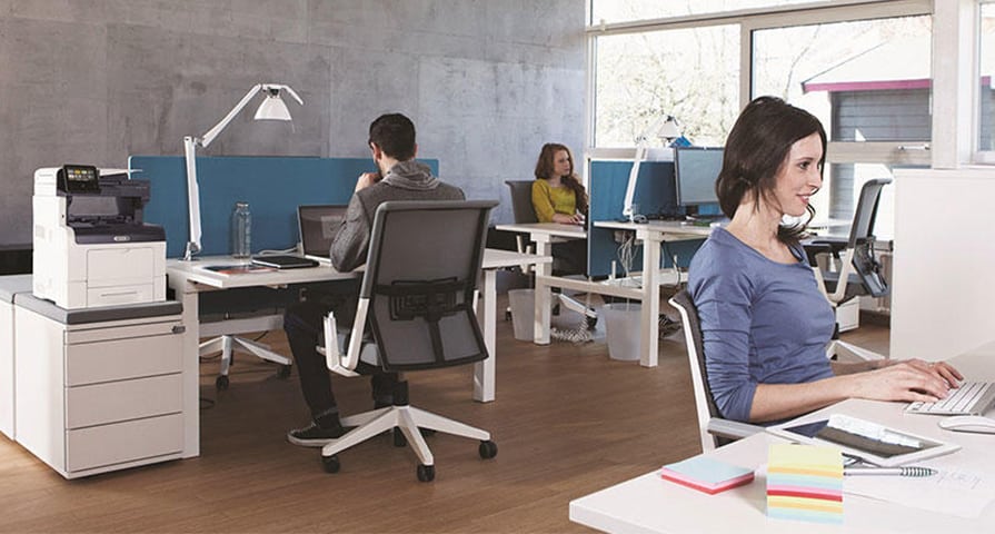 Office workers at their desks around the office print devices