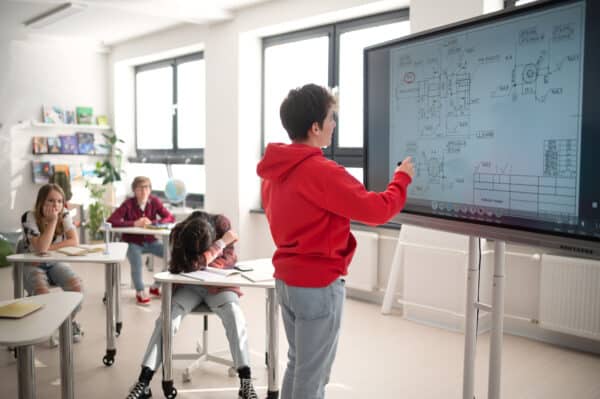 student using smart board in front of class
